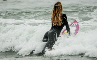 Woman surfing pink surfboard beach - flowing hair free wallpaper