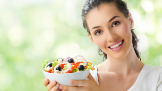 Woman smiling holding salad green - a green background behind her free wallpaper