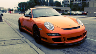 Orange sports car parked city - the side of the road in front free wallpaper