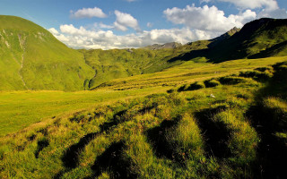 Grassy valley mountains clouds sky - free landscape wallpaper
