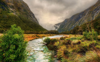 Lush green river valley mountains - a lush green valley under a cloudy sky free wallpaper