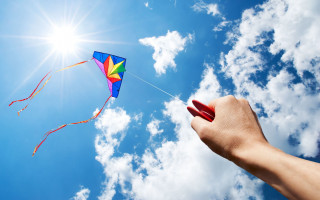 Kite flying sun clouds ocean - a bright sun in the background free wallpaper
