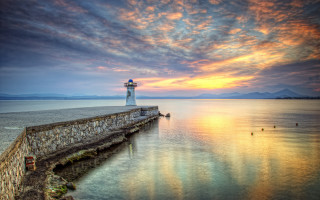 Lighthouse sunset pier clouds water - a body of water below free wallpaper