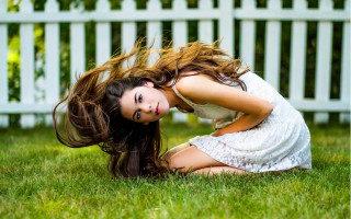 Woman kneeling grass wind whitefence - flowing hair free wallpaper