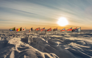 Flags snow ocean sunset beach - the sun shining behind them free wallpaper