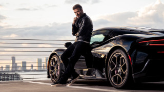 Man black sports car city - a city skyline in the background free wallpaper