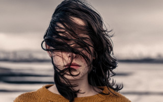 Woman blowing hair brown sweater - a boat in the background free wallpaper