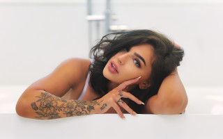 Tattooed woman leaning on wall - a wall free wallpaper