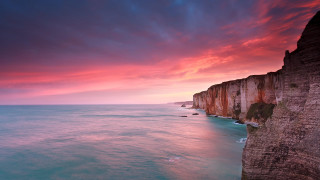 Sunset cliff water red sky - a body of water below free wallpaper
