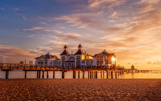 Pier building sunset clouds water - a body of water below free wallpaper