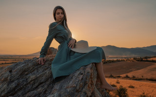 Woman sitting rock hat sunset - her head and a dress free wallpaper