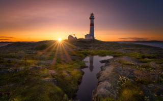 Lighthouse rocky outcrop sunset water - the background and a body of water free wallpaper