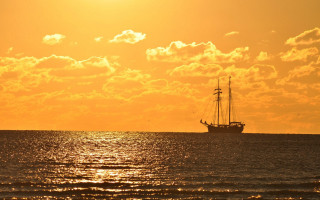 Sailboat ocean sunset clouds yellow - golden hour free wallpaper