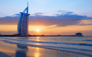 Tall building beach ocean sunset - a boat in the background free wallpaper