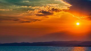 Sunset mountains water boat sail - a sunset over a body of water free wallpaper