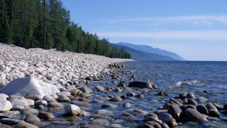 Rocky shore mountain forest water - the background and a mountain range in the distance free wallpaper