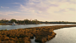 River boat grassy sunset cityscape - a boat in the distance free wallpaper