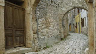 Narrow cobblestone street romanque arch - a wooden door free wallpaper