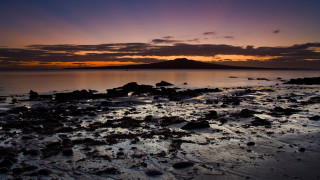 Sunset water rocks sand mountain - a sunset over a body of water free wallpaper