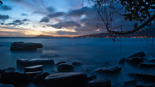 Water rocks city cloudy sunset - a view of a body free wallpaper