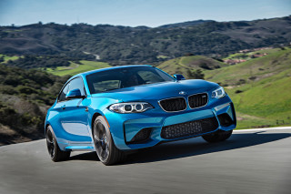 Blue bmw driving hillside landscape - a green hillside in the background free wallpaper
