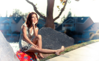 Woman sitting rock tree houses - the background and a tree in the foreground free wallpaper