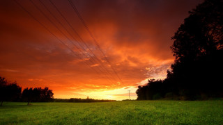 Sunset powerlines green field mountain - a red sky above free wallpaper