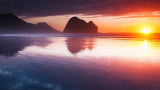 Sunset beach mountain water sky - a mountain in the background and a body of water free wallpaper