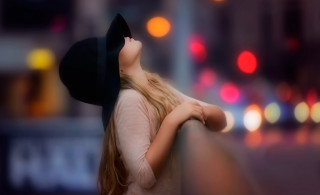 Woman leaning wall blonde hat - a city street in the background free wallpaper