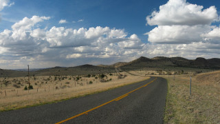 Road field mountains clouds sky - a yellow line free wallpaper