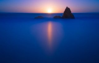 Rock ocean sunset bright sky 2 - a bright sun in the background free wallpaper