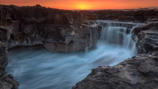Waterfall sunset river rocks cloudy - a sunset in the background and a body of water free wallpaper