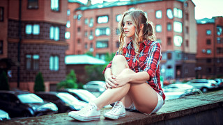 Woman eskter mattioni city sitting - a ledge in front free wallpaper