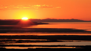 Sunset water mountains orange sky - a sunset over a body of water free wallpaper