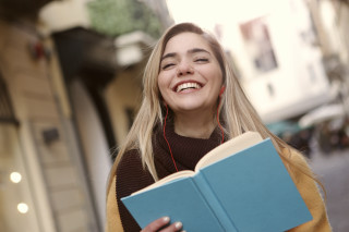 Woman smiling holding book headphones - headphone free wallpaper