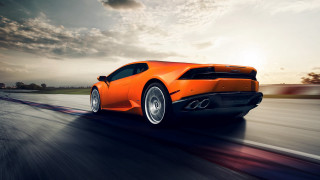 Bright orange sports car sunset - a cloudy sky in the background free wallpaper