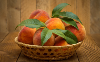 Basket peaches leaves wooden table - a wooden table top free wallpaper