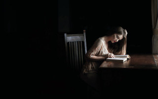 Woman sitting reading dark window - a window behind her free wallpaper
