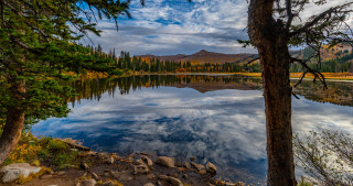 Lake mountains trees clouds nature 2 - tree and mountains under a cloudy sky free wallpaper