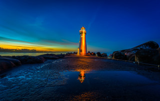 Lighthouse rocky shore sunset reflection - a reflection free wallpaper