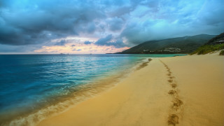 Beach footprints mountain clouds ocean - the water and a mountain in the distance free wallpaper