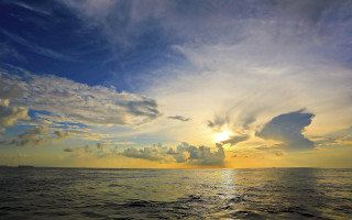 Sunset ocean boat clouds city - a boat in the distance free wallpaper