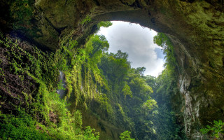 Cave entrance waterfall lush green - a cloudy sky free wallpaper