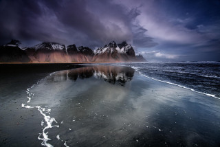 Beach mountains city lights night - a dark sky free wallpaper