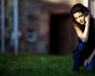 Woman sitting grass talking cellphone - a building in the background free wallpaper