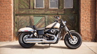 Motorcycle parked wooden door sidewalk - a brick wall behind free wallpaper
