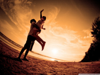 Beach sunset man woman orange - the sun setting behind them free wallpaper