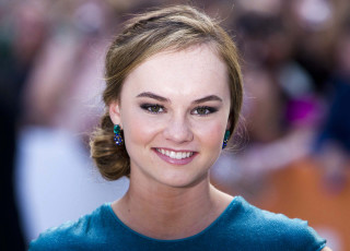 Woman blue dress earrings smiling - a crowd in the background free wallpaper