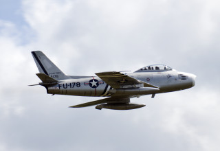 Silver airplane flying blue sky - a few white cloud free wallpaper