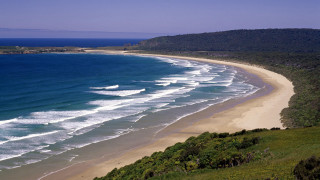Beach sandy shore large water - a hill in the background free wallpaper